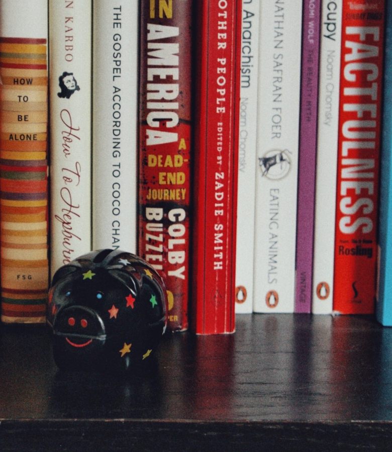 black piggybank on a shelf and several books in the background