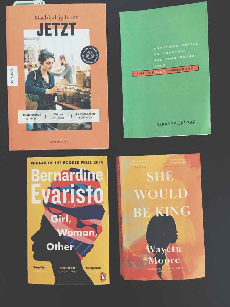 four books on a black table, three english titles, one german title